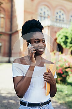 Pretty african american college student making a phone call in campus