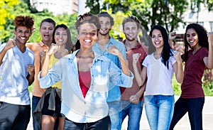 Pretty african american female student with group of cheering young adults