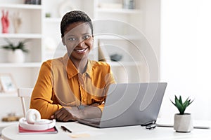 Pretty african american lady freelancer using laptop at home