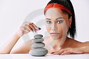 Pretty african american woman doing pyramid of the stones on white background