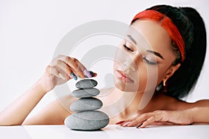 Pretty african american woman doing pyramid of the stones on white background