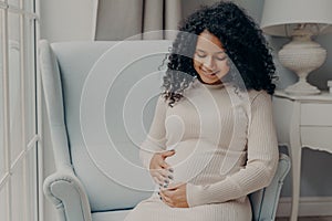 Pretty african american woman holding her belly in anticipation of future baby