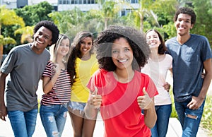 Pretty african american woman showing thumb up with international friends