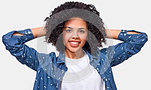 Pretty African American young woman dressed in white t-shirt and blue blouse, holding hands on head, feeling happy.