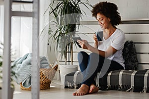 Pretty African American young woman reading an eBook at home