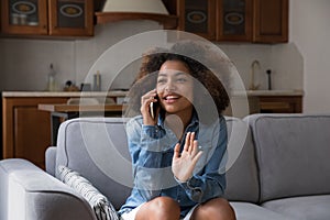 Pretty African teenage girl sits on sofa blab on cellphone