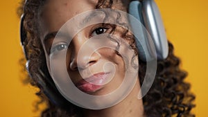 Pretty african woman listening music, dance her head with headphones on yellow