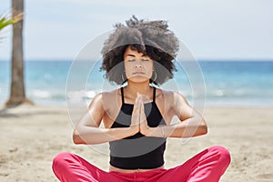 Pretty afro american woman meditating on beach