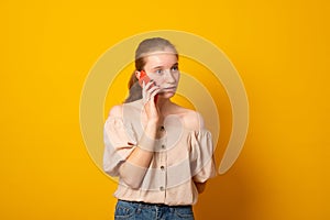 Pretty american girl has telephone conversation keeps smartphone near ear with gentle smile isolated