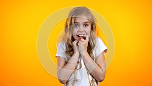 Pretty anxious blond girl biting finger and looking to camera, suffering fear