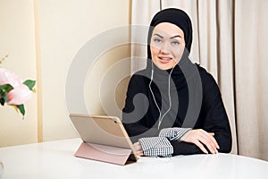 Pretty Arabian teen girl using tablet computer in high school classroom