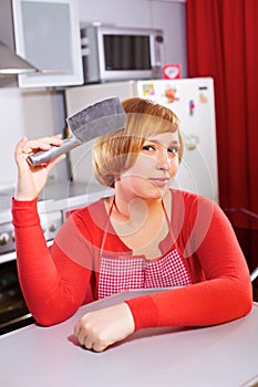 Pretty artful housewife with knife at kitchen