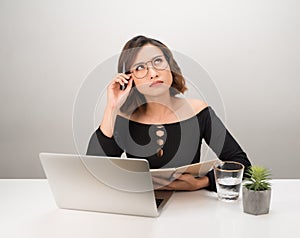 Pretty Asian business woman thinking at her desk in her office