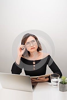 Pretty Asian business woman thinking at her desk in her office