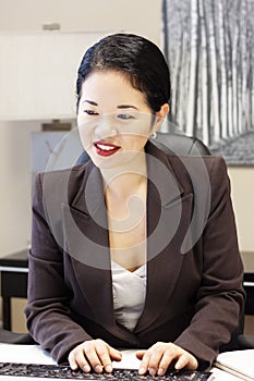 Pretty asian businesswoman typing
