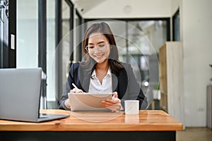 Pretty Asian businesswoman using digital tablet at her office desk