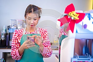 Pretty asian cashier was using a phone application to manage customer transactions, Smart technology, Bussiness and finance