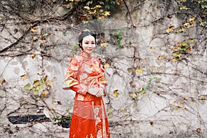 Young, beautiful and elegant Chinese woman wearing a typical Chinese bride`s silk red dress, adorned with golden phoenix and drago
