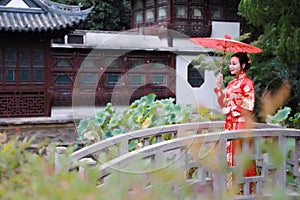 Young, beautiful and elegant Chinese woman wearing a typical Chinese bride`s silk red dress, adorned with golden phoenix and drago