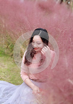 Pretty Asian Chinese woman beautiful girl outdoor sit on grass lawn in a park garden feel carefree caucasian pasttime read book