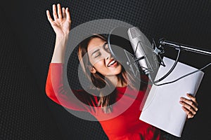 Pretty Asian female singer recording songs by using a studio microphone and pop shield on mic with passion in music recording