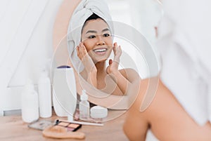 Pretty asian girl applying cream on her face
