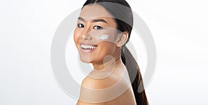 Pretty asian girl applying moisturizer cream on face