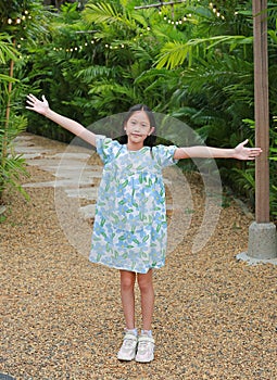 Pretty Asian girl arms outstretched or keeping arms raised while standing in the garden