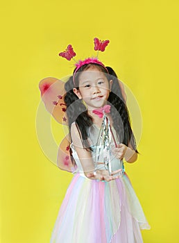 Pretty asian girl dressed in fairy costume with looking camera isolated on yellow background