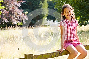Pretty Asian Girl Sitting On Fence In Countryside