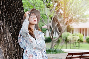 Pretty asian girl in vintage dress leaning against on the tree and relaxing