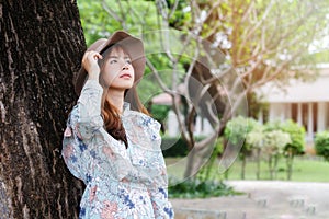 Pretty asian girl in vintage dress leaning against on the tree and relaxing