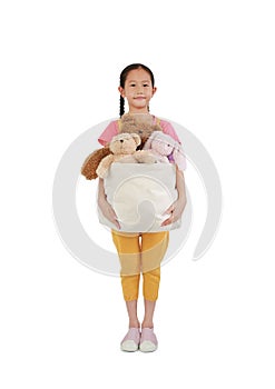 Pretty Asian little girl child holding toys bag for donation. Kid hold bag of dolls isolated on white background. Concept of Pass