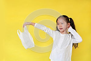 Pretty asian little girl needless a white thin polythene plastic bag for Reduce or zero waste. Kid holding a plastic bag isolated