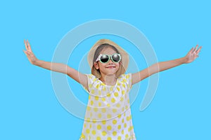 Pretty asian little girl wearing a sunglasses and straw hat with open wide arms isolated on light blue background with clipping