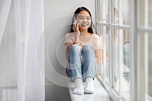 Pretty asian school-aged girl having phone conversation at home