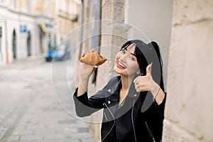 Pretty Asian smiling lady having lunch time outdoor in old European city. Mixed raced woman tourist sitting on the