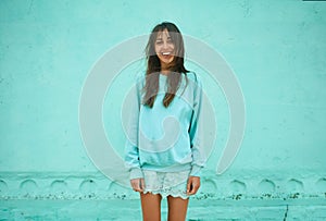 pretty asian woman in blue sweatshirt with long darke hair smiling over blue background