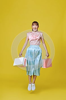 Pretty Asian woman carrying colorful shopping bags in purple color studio background