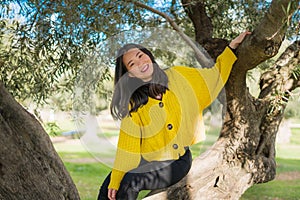 Pretty Asian woman in city park - lifestyle portrait of young beautiful and happy Japanese girl playful by a tree enjoying