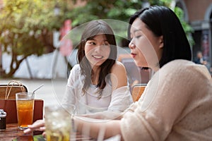 A pretty Asian woman enjoys talking chitchat with her friend while hanging out at an outdoor cafe photo