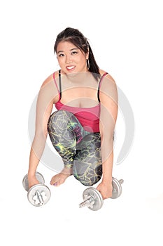 Pretty Asian woman kneeling with two dumbbells