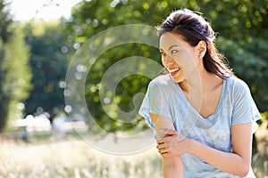 Pretty Asian Woman Sitting On Fence In Countryside