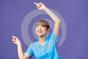 pretty asian woman smiling happily and pointing to side and upwards with both hands showing object