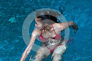 Pretty Asian woman wearing red bikini swimming at swimming pool and enjoying travel on vacation summer time.