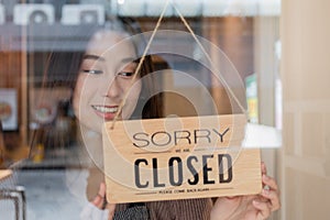 Pretty asian young owner retail, coffee shop woman turning sign board to closed after finished work, job and protection to