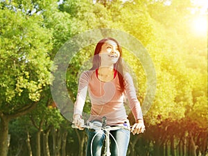 Pretty asian young woman riding bike in the park