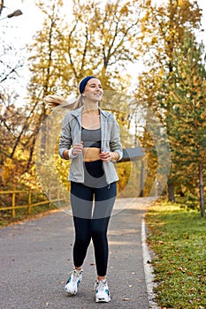 Pretty athletic female running at sunny autumn day