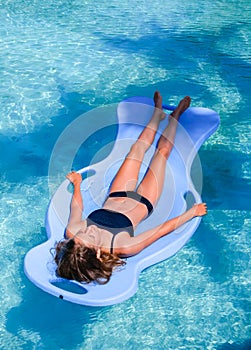 Pretty athletic sun tanned girl floating on a pool float in a swimming pool on vacation