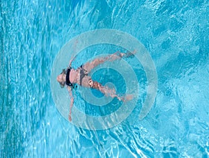 Pretty athletic sun tanned girl floatingin a swimming pool on vacation